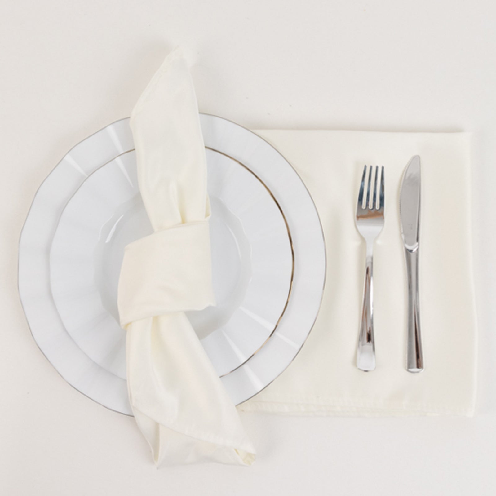 Ivory satin dinner napkins on a table setting with plate and cutlery.