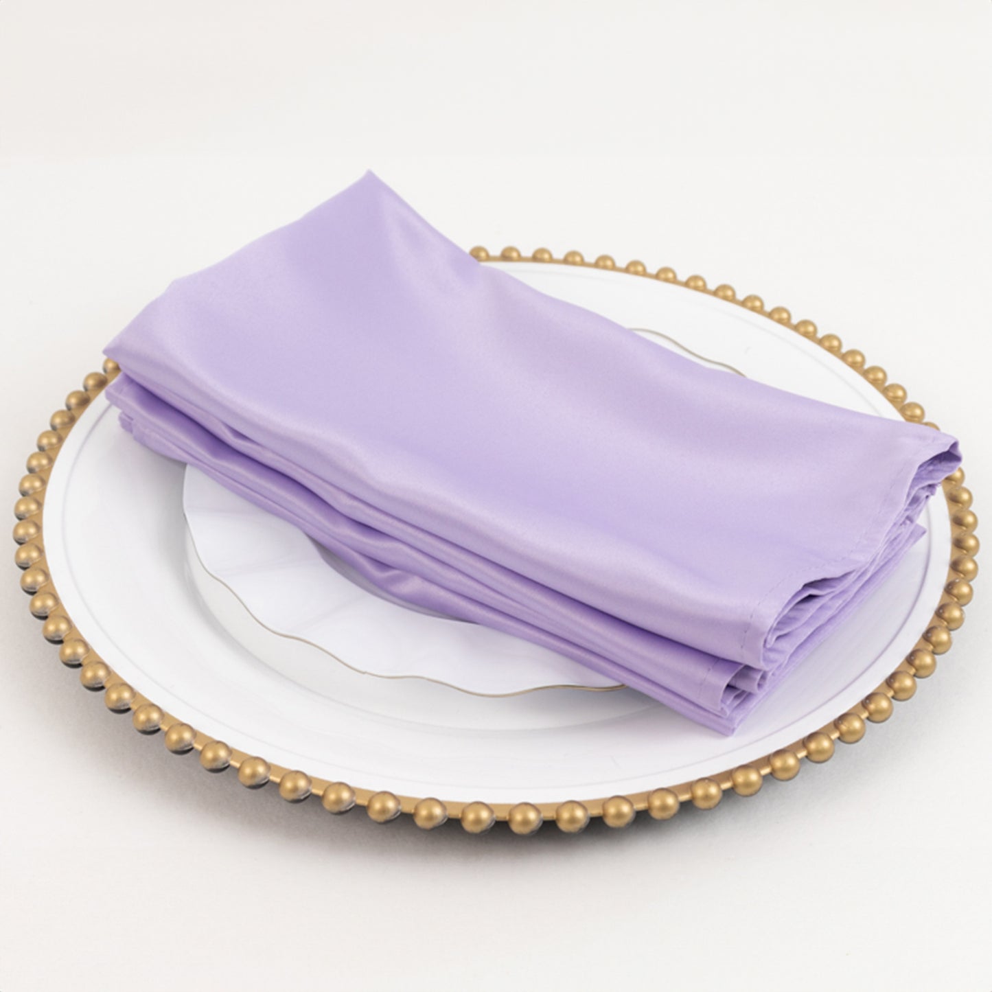 Lavender lilac satin napkins stacked on a decorative plate.