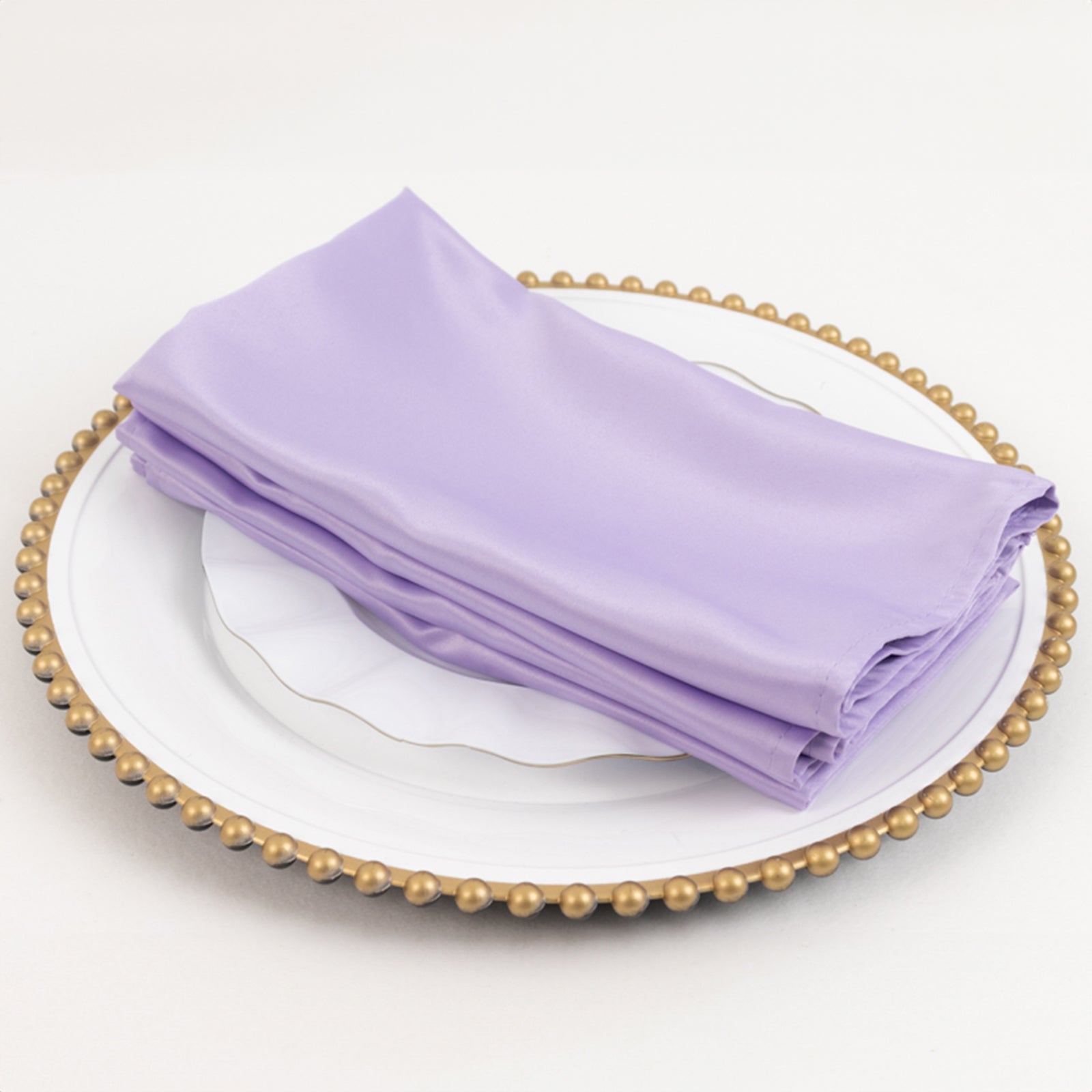 Lavender lilac satin napkins stacked on a decorative plate.