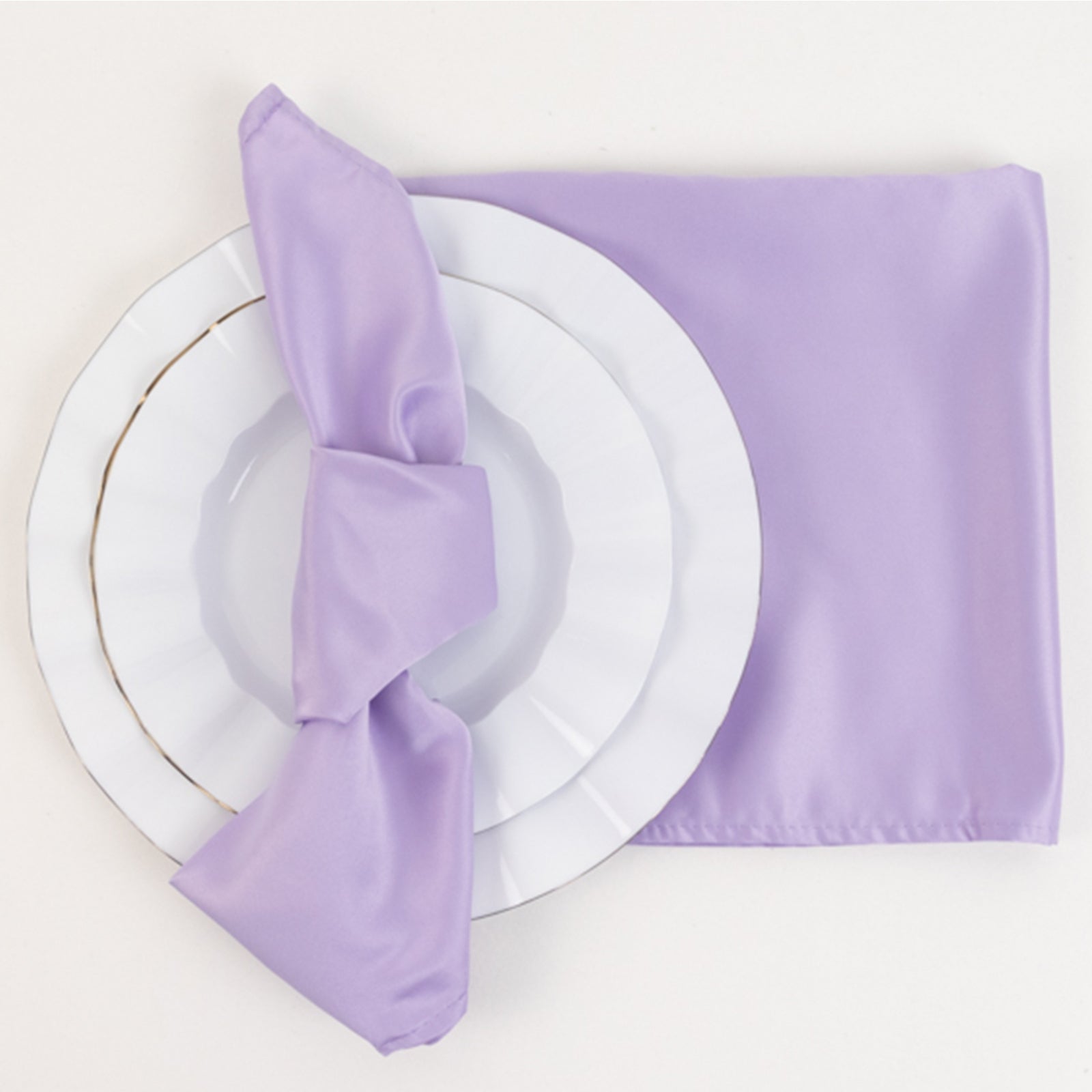 Lavender lilac satin napkins on a white plate with a matching napkin.