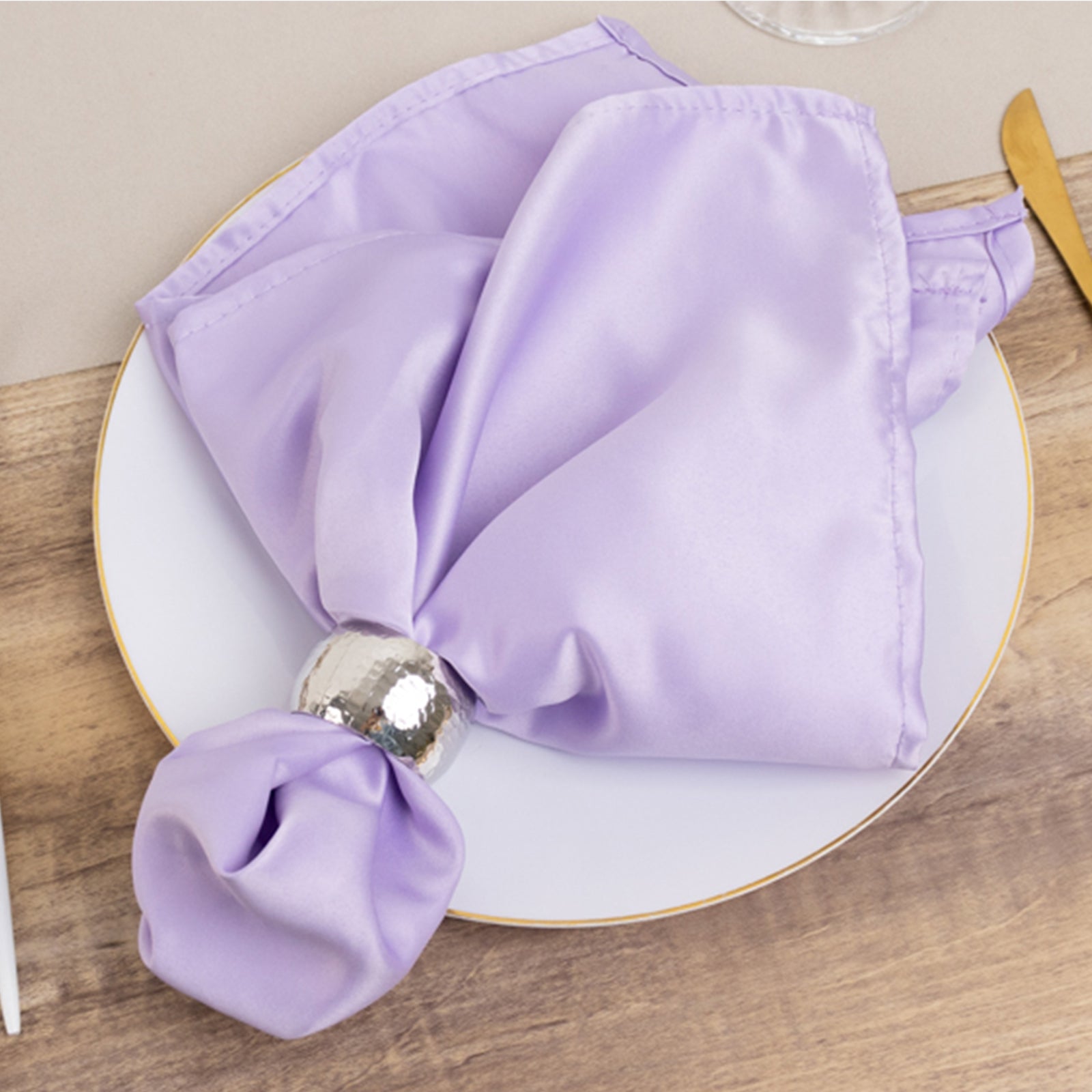 Lavender lilac satin napkin elegantly folded on a dining plate.