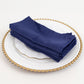 Navy blue satin napkins stacked on a decorative plate.