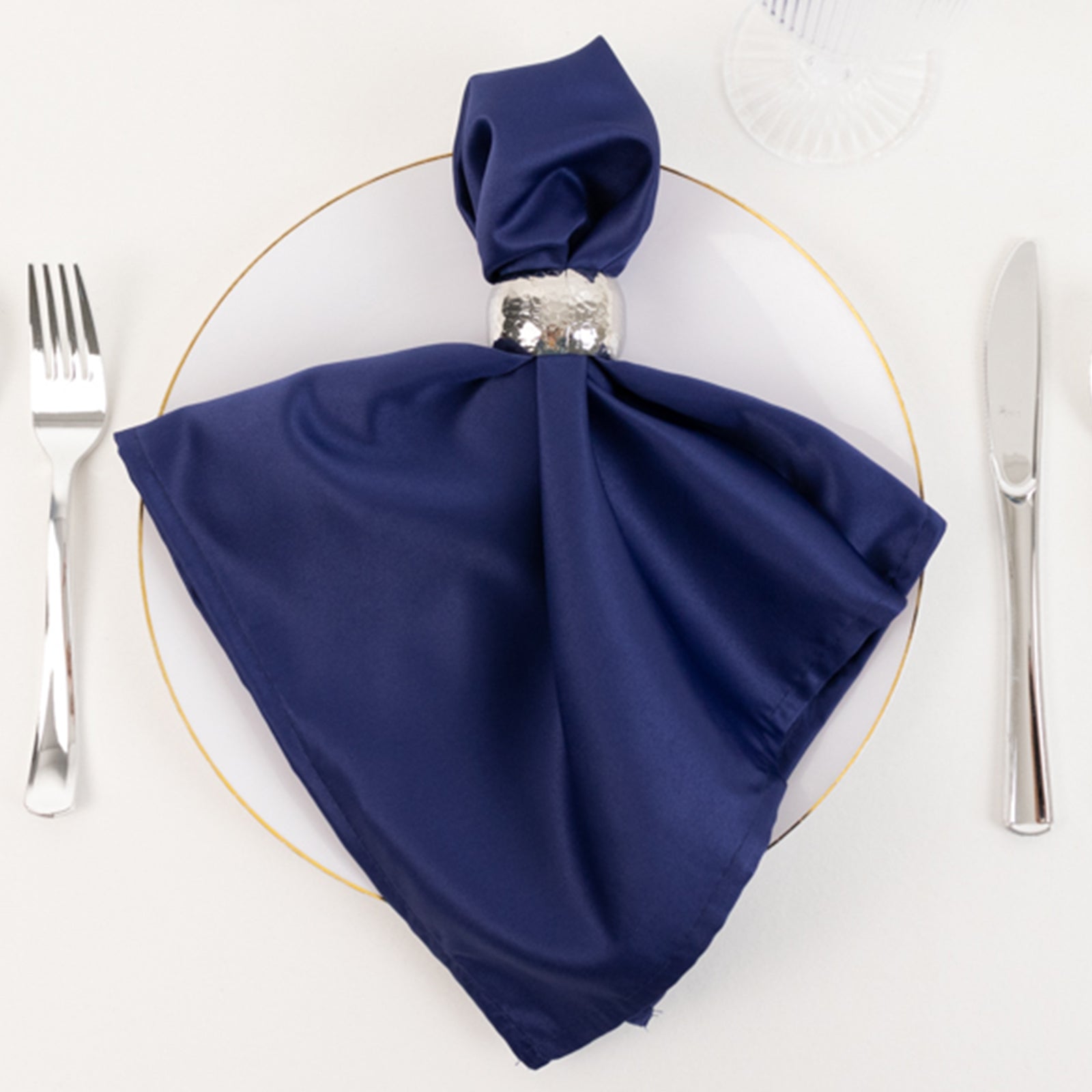 Navy blue satin napkin elegantly displayed on a dinner plate.