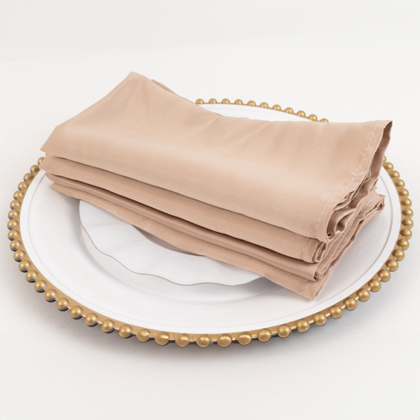 Nude satin napkins, 20"x20", set of 5, elegantly folded on a decorative plate.