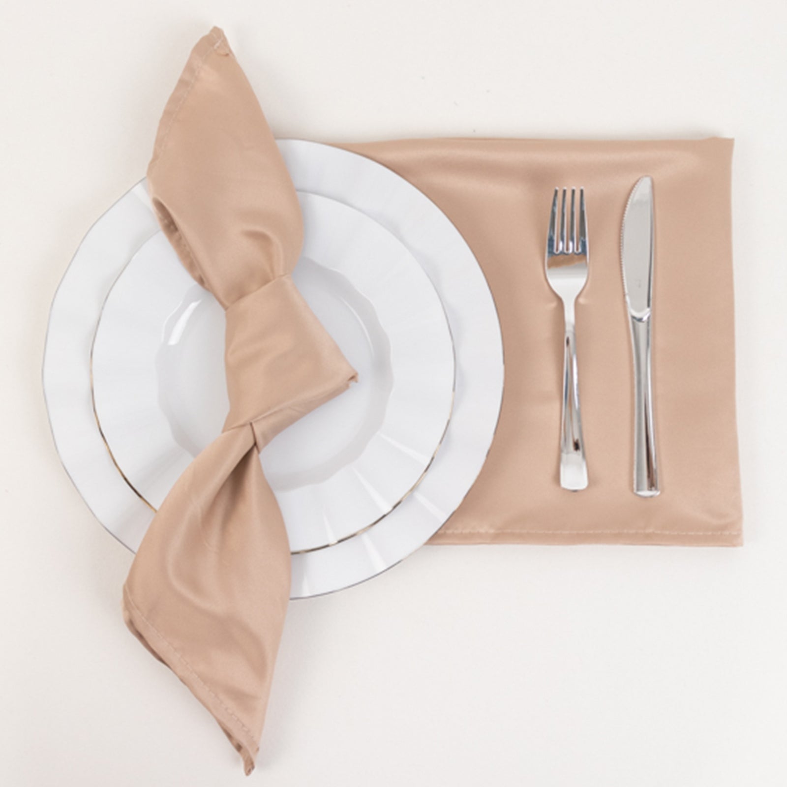 Nude satin napkins arranged with a plate, fork, and knife.