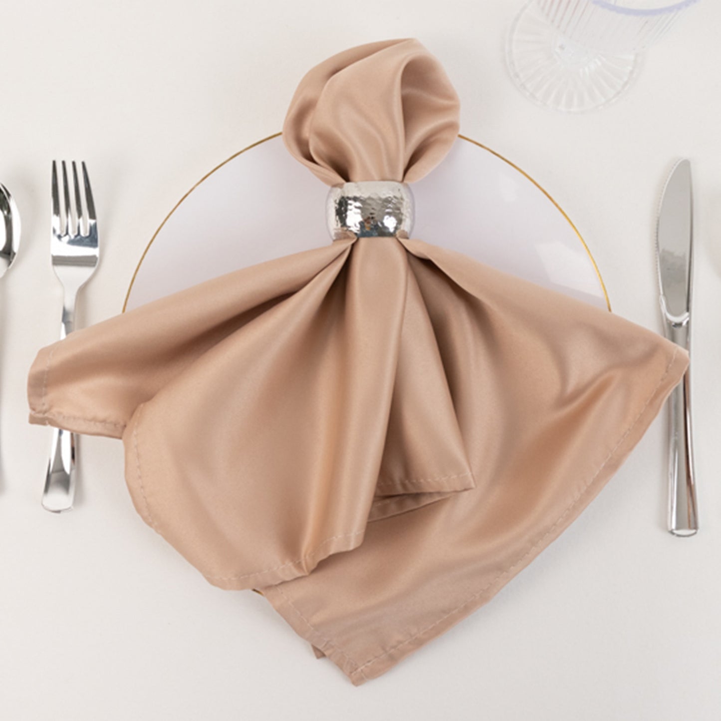 Nude satin napkin elegantly arranged on a dinner plate.