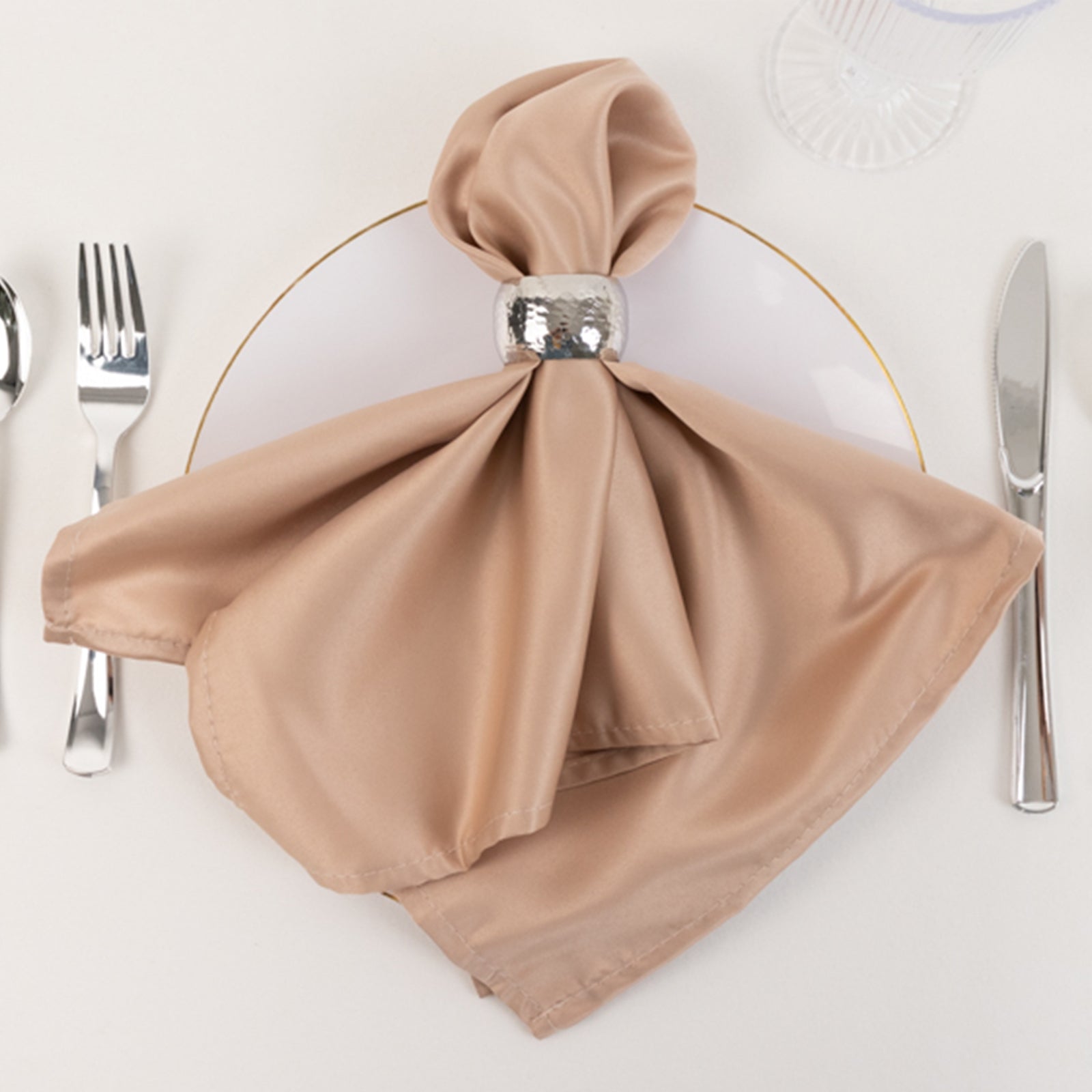 Nude satin napkin elegantly arranged on a dinner plate.