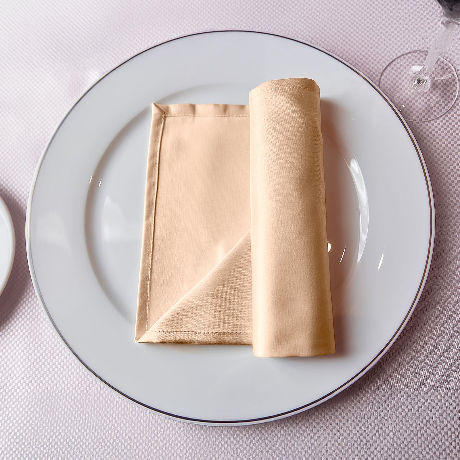 Nude satin napkins on a white plate, elegantly arranged for dining.