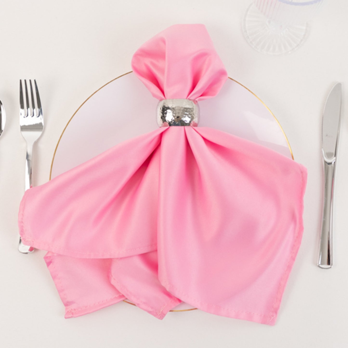 Pink satin napkin elegantly arranged on a plate.