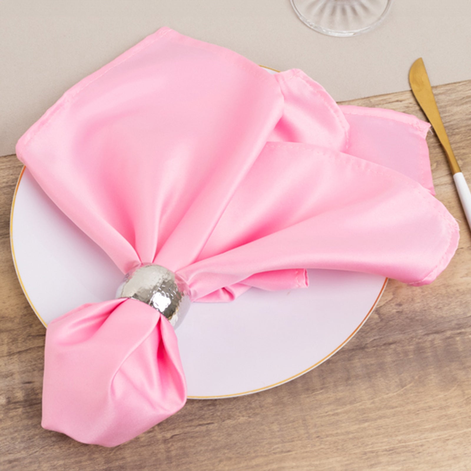 Pink satin napkins elegantly arranged on a plate.