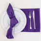 Purple satin napkins on a table setting with white plates and silver cutlery.