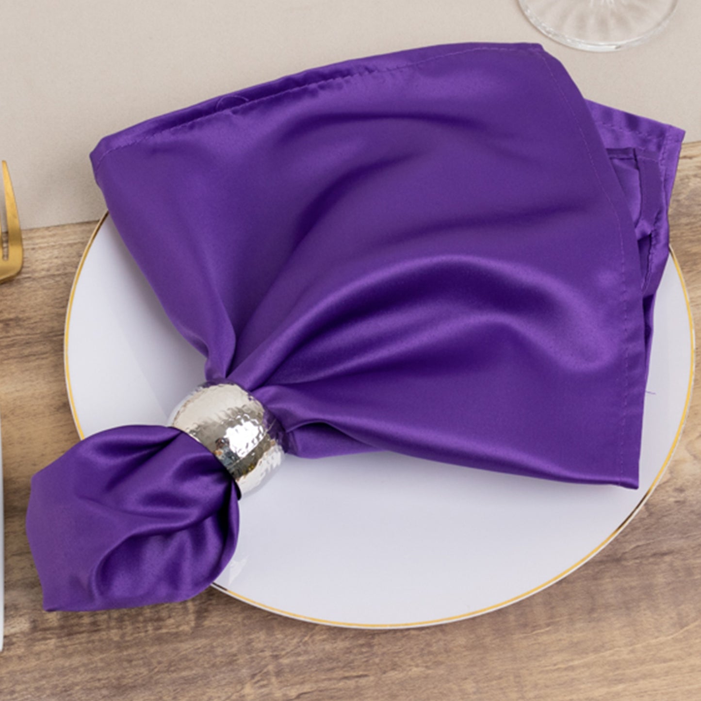 Purple satin napkin elegantly arranged on a plate.