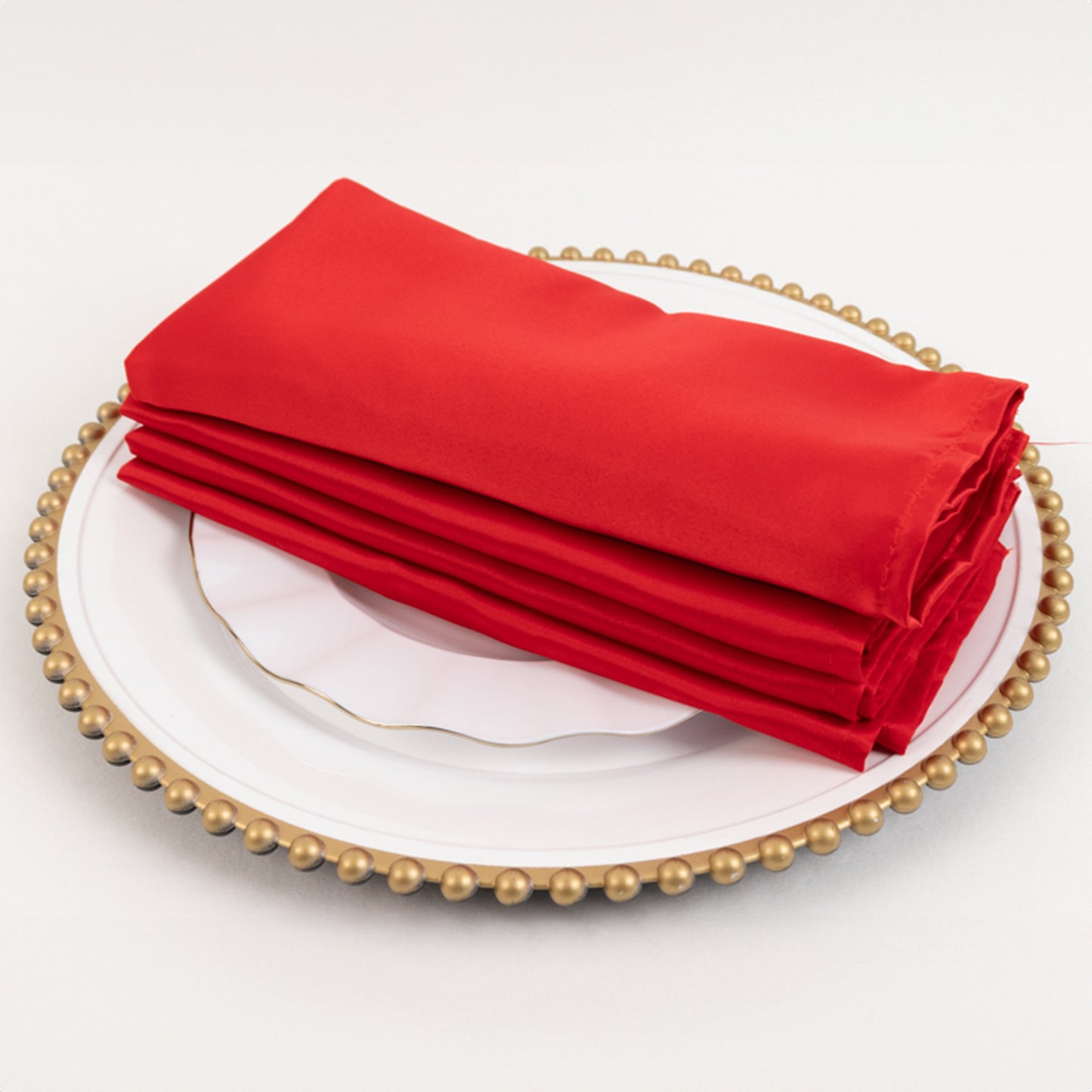 Red satin napkins stacked on a decorative plate.