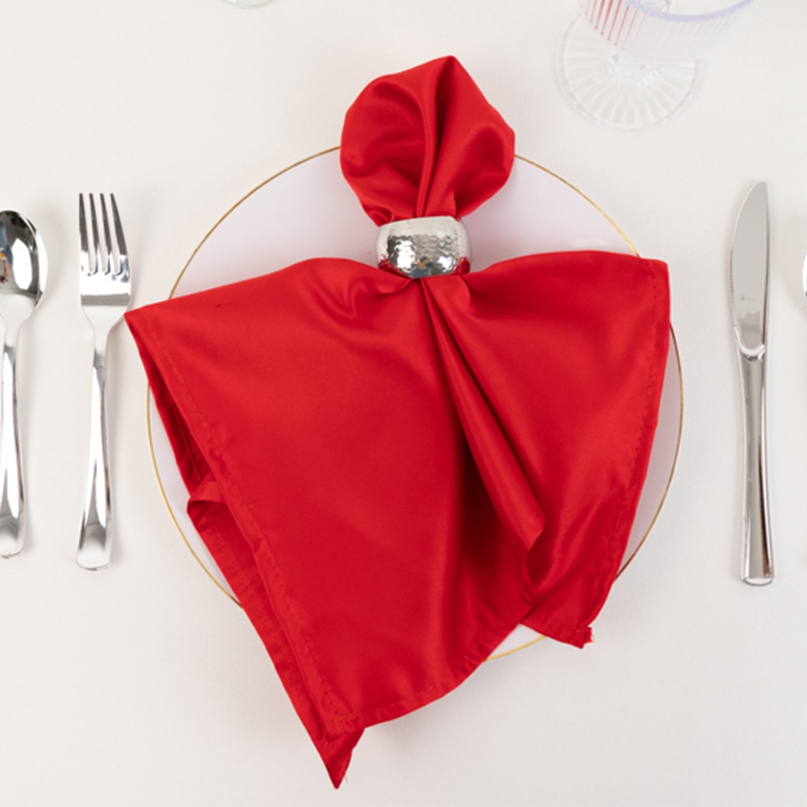 Red satin napkin arranged elegantly on a plate.