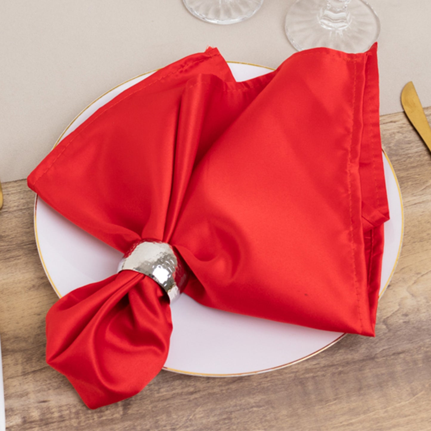 Red satin napkin elegantly styled on a plate with a napkin ring.