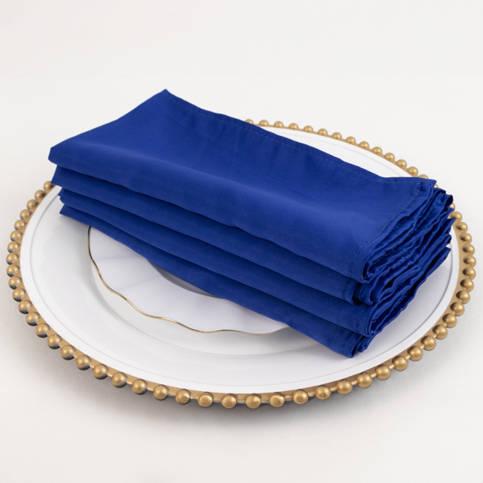 Lamour Satin Napkins - Royal Blue, 20"x20", 5 Pack on a decorative plate.