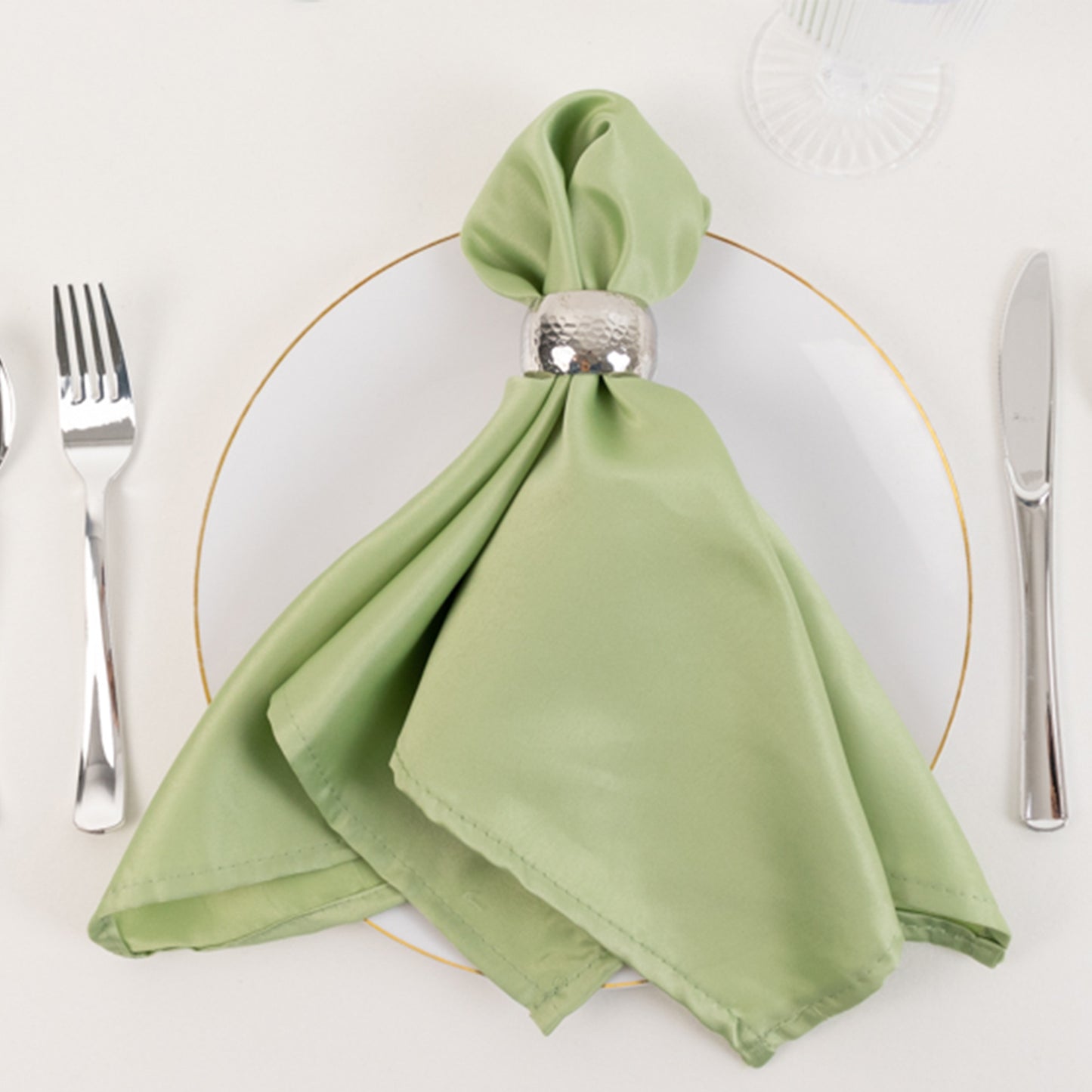 Sage green satin napkin elegantly displayed on a white plate.