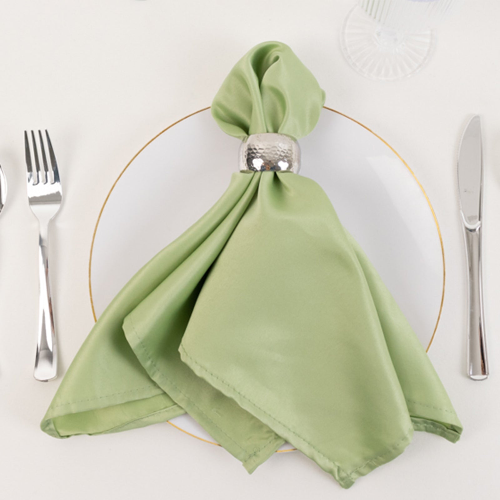 Sage green satin napkin elegantly displayed on a white plate.