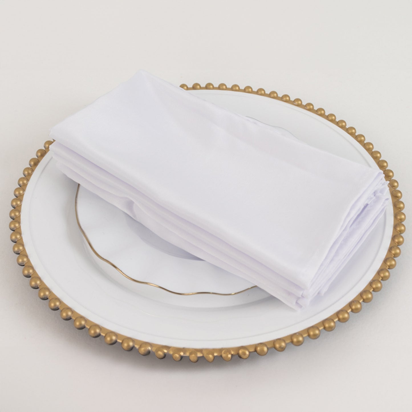 White satin napkins on a decorative plate.