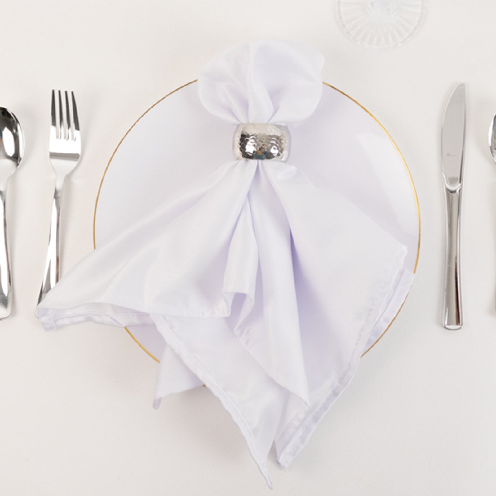 White satin napkins on a plate, elegantly folded.