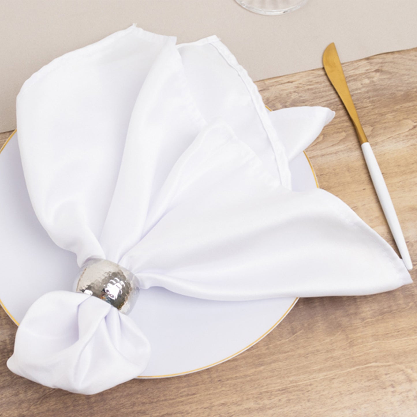 White satin napkin elegantly styled on a plate with a gold fork.