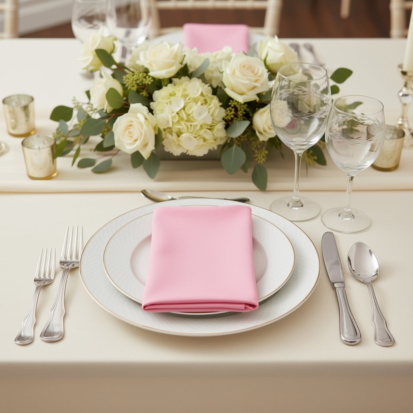 Pink scuba napkins on a dining table set with flowers and glassware.