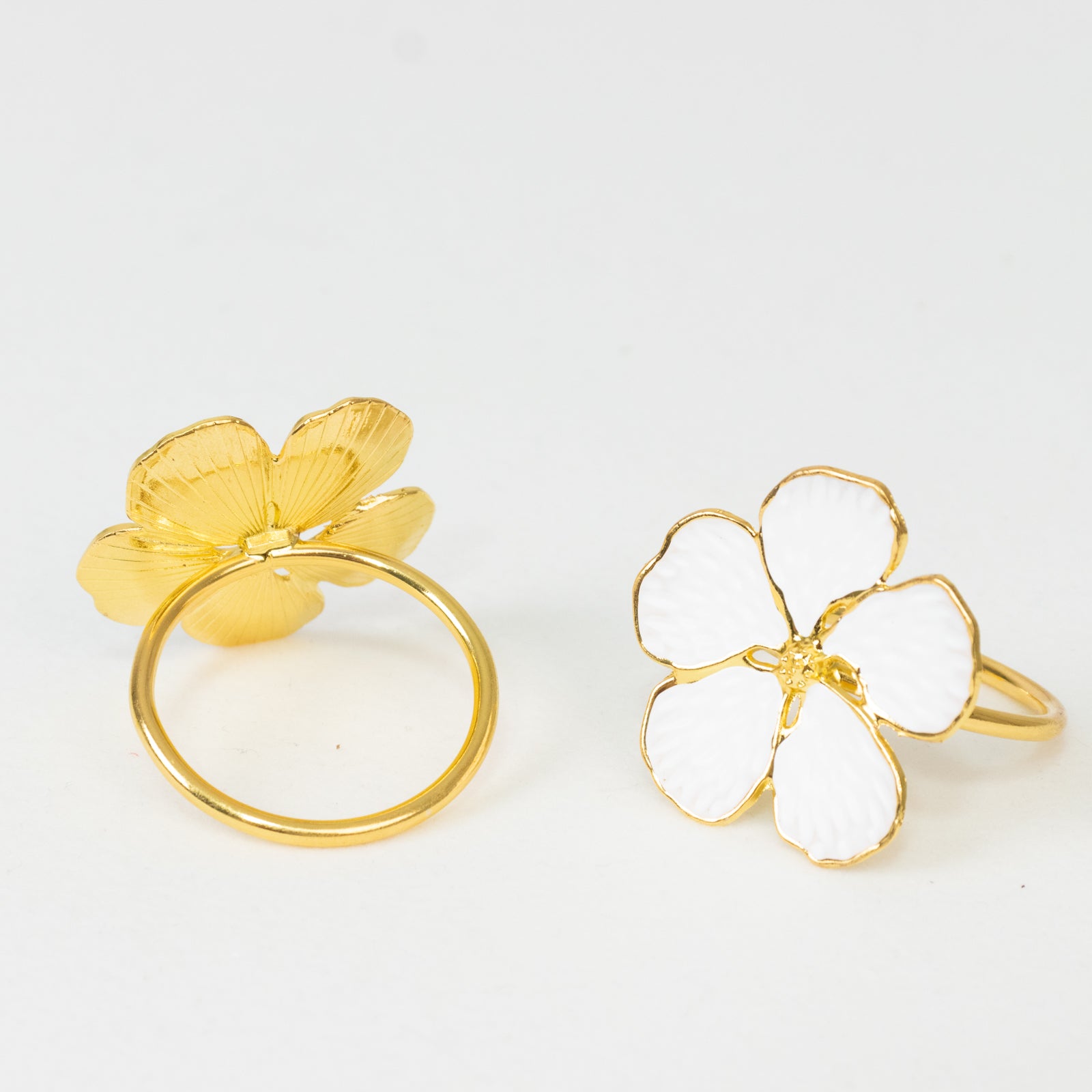 White and gold metal flower napkin rings in plum blossom design.