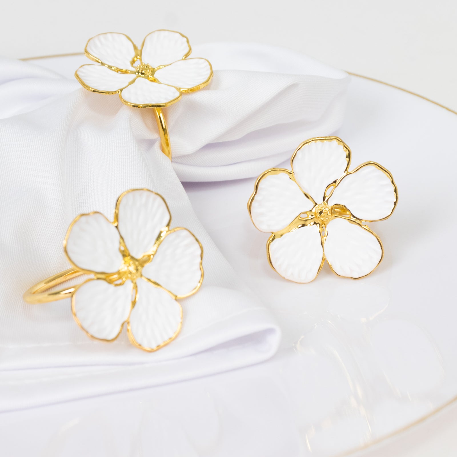 White and gold floral napkin rings on a white napkin.