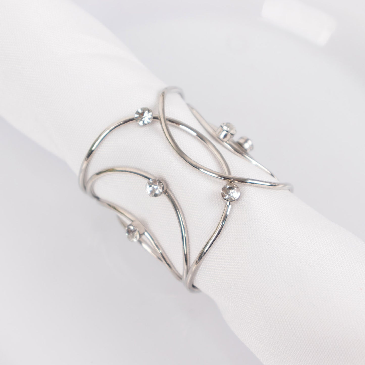 Silver metal napkin rings with rhinestones in a woven design.