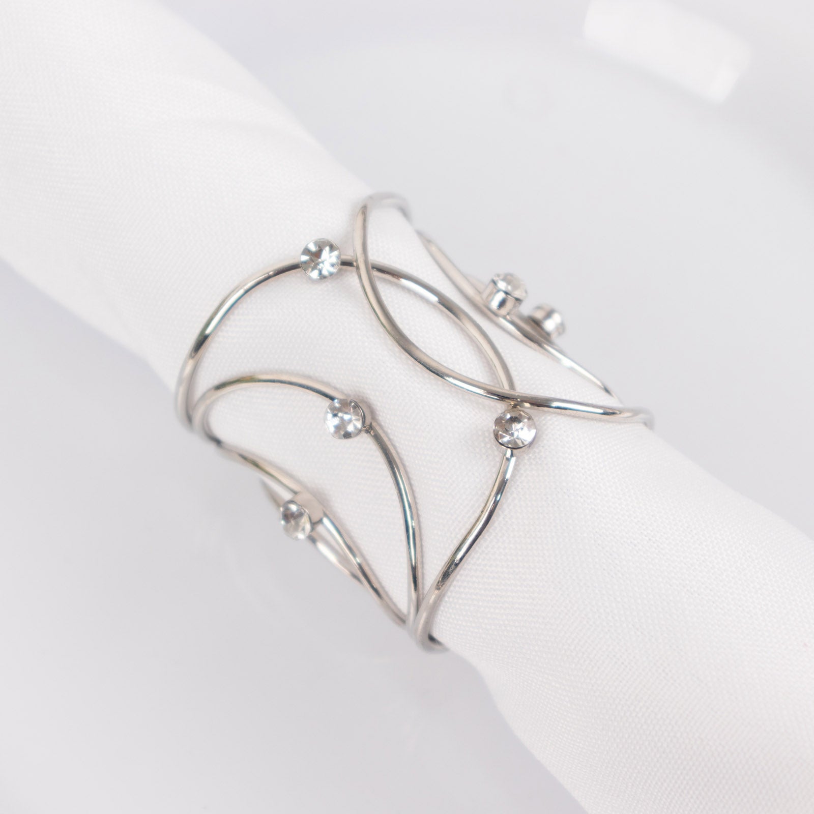 Silver metal napkin rings with rhinestones in a woven design.