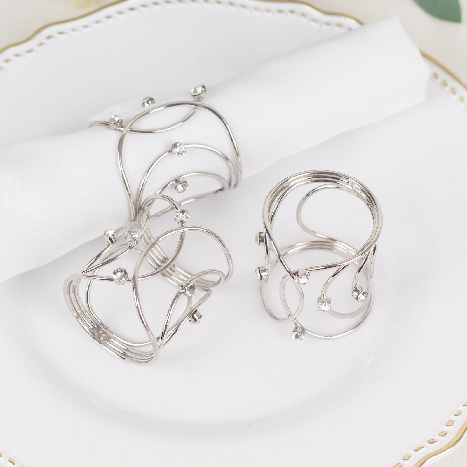 Silver metal napkin rings with rhinestones, elegant woven design.