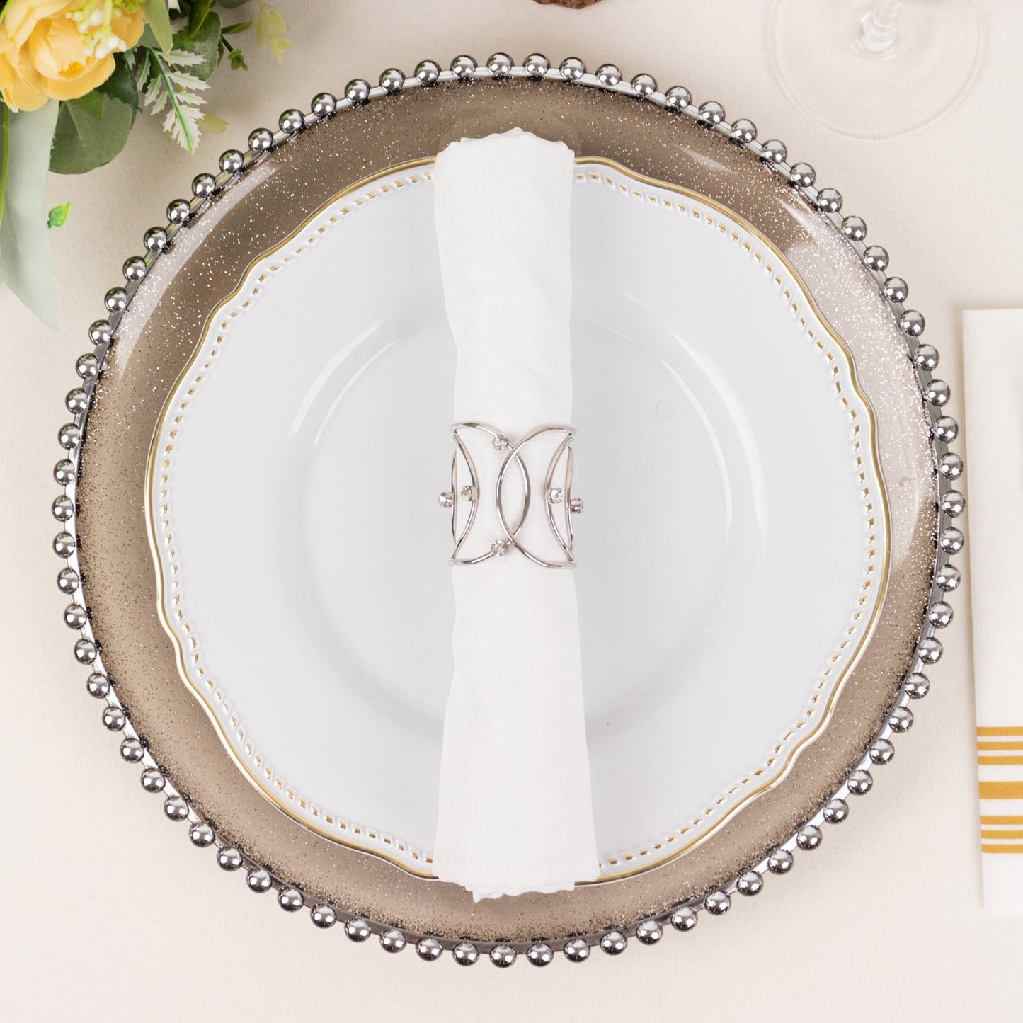 Silver metal napkin ring with rhinestones on a white napkin. Elegant table setting.