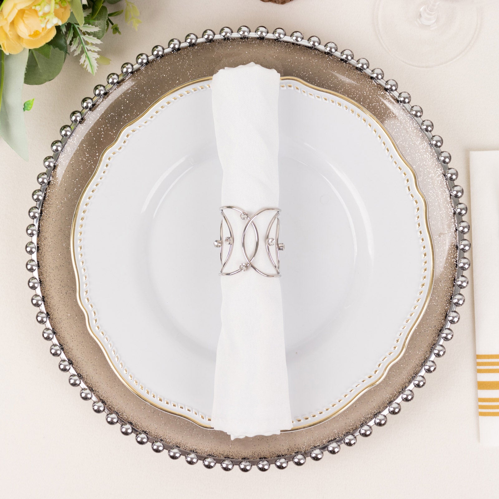 Silver metal napkin ring with rhinestones on a white napkin. Elegant table setting.