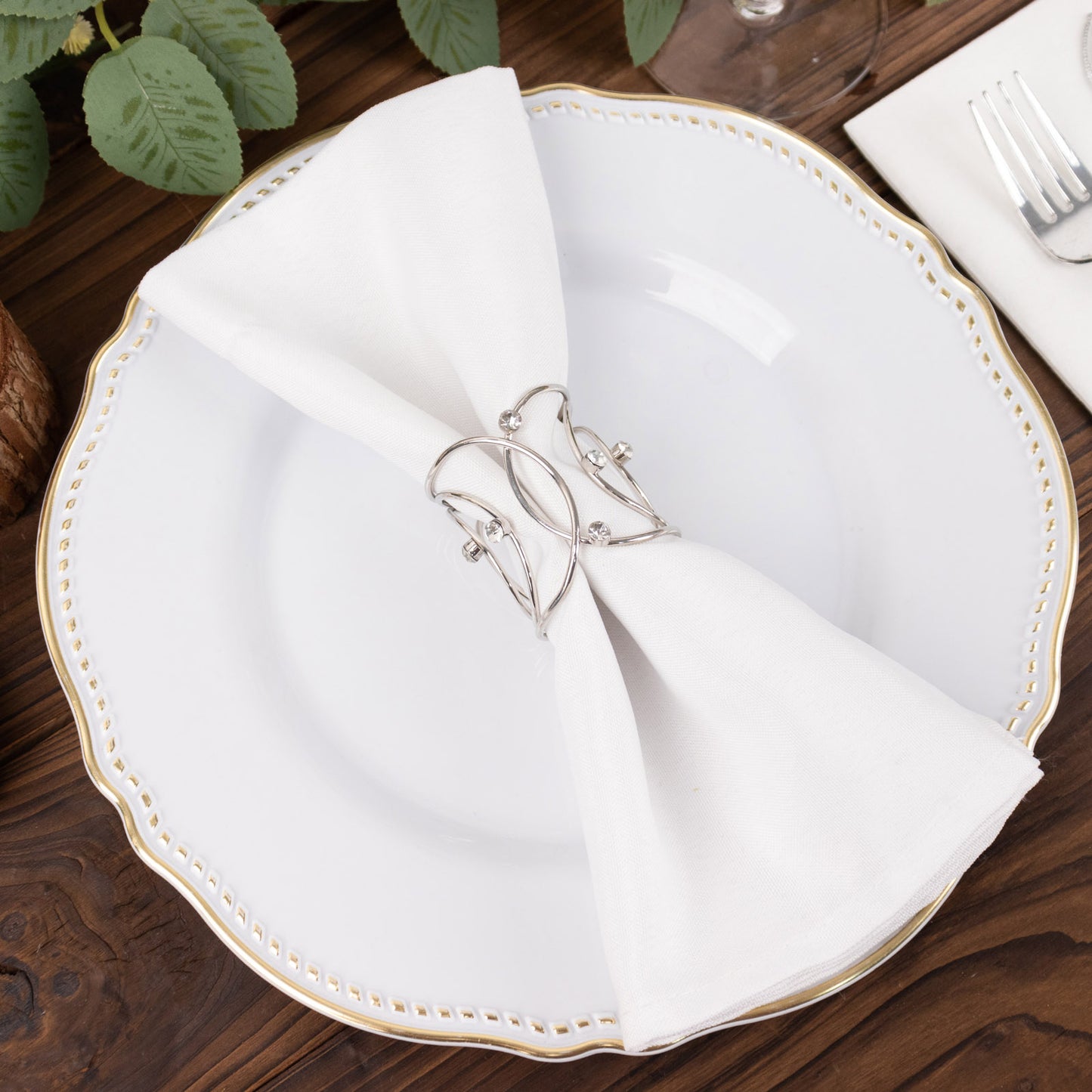 Silver metal napkin rings with rhinestones on a white napkin.