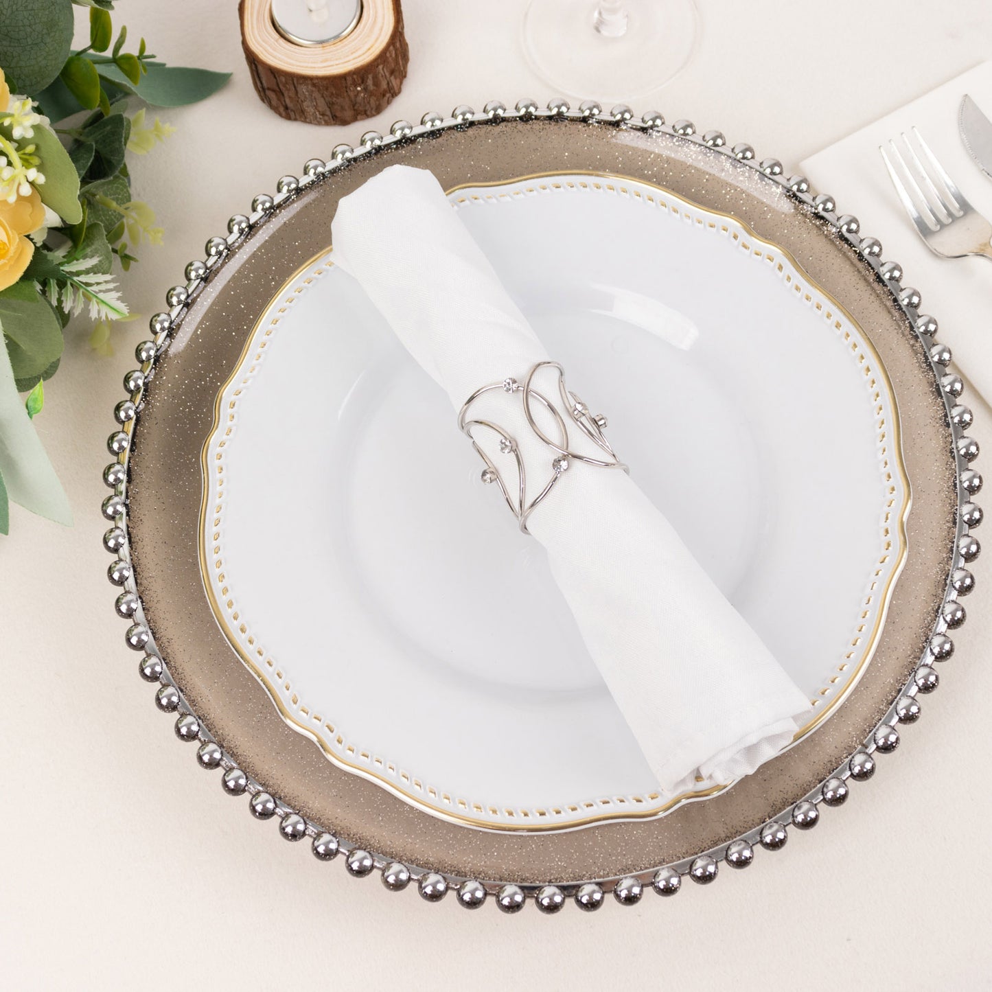 Silver metal napkin rings with rhinestones on a white napkin.