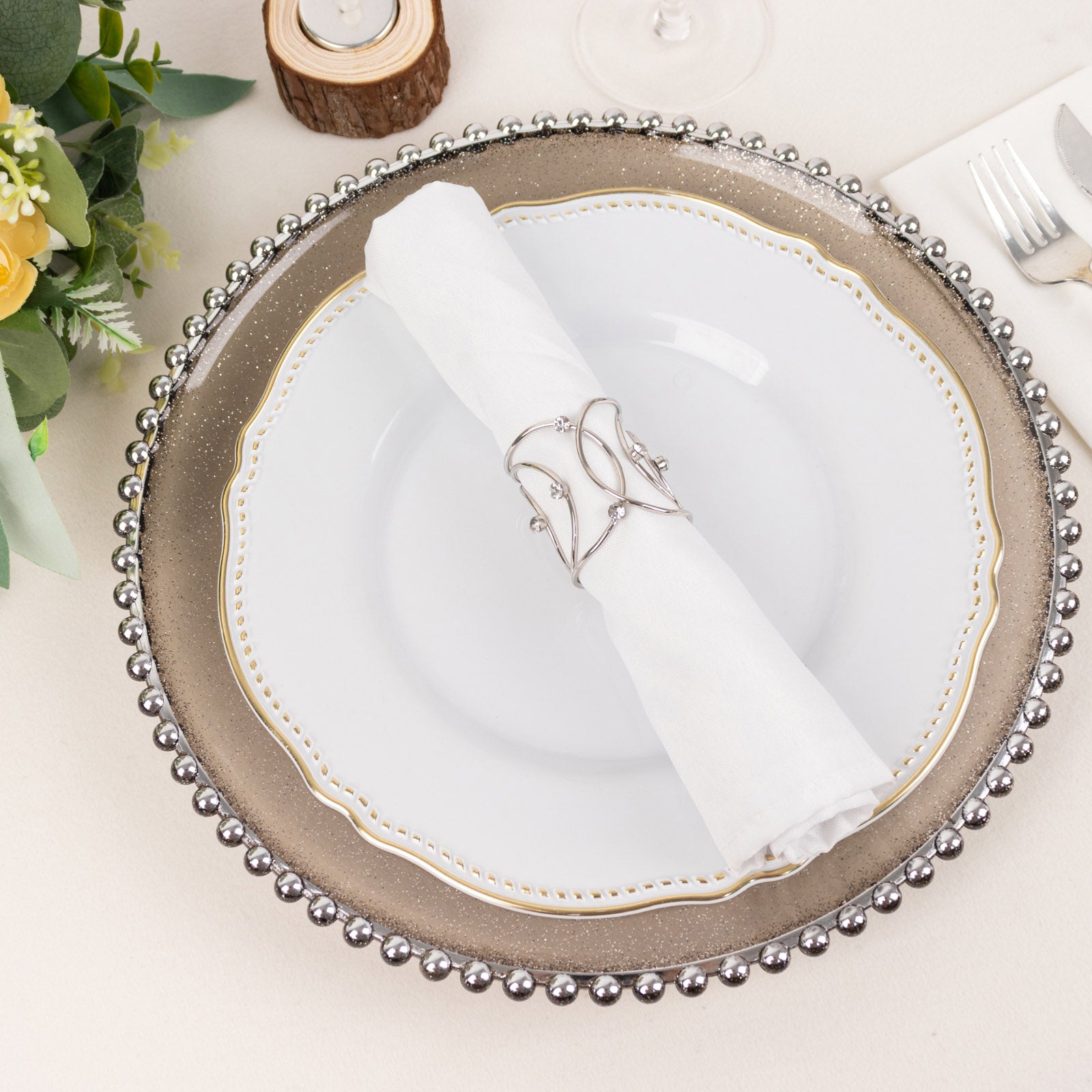 Silver metal napkin rings with rhinestones on a white napkin.
