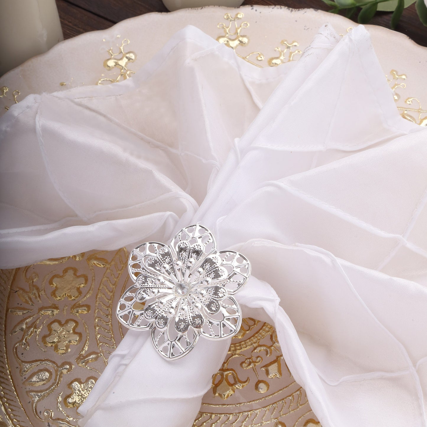 Silver metal hollow sun flower napkin ring on a white napkin.
