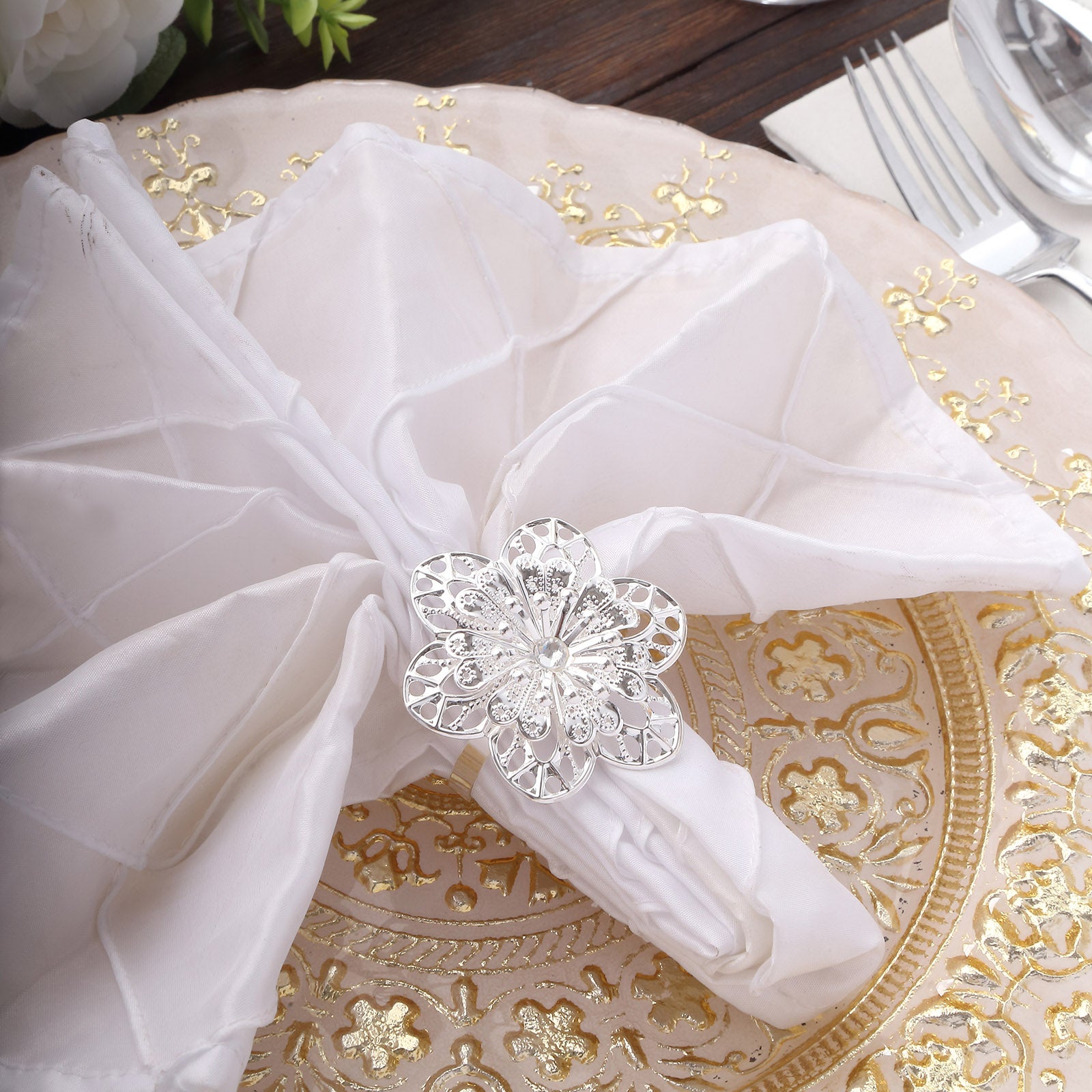Silver metal hollow sun flower napkin ring on a white napkin.