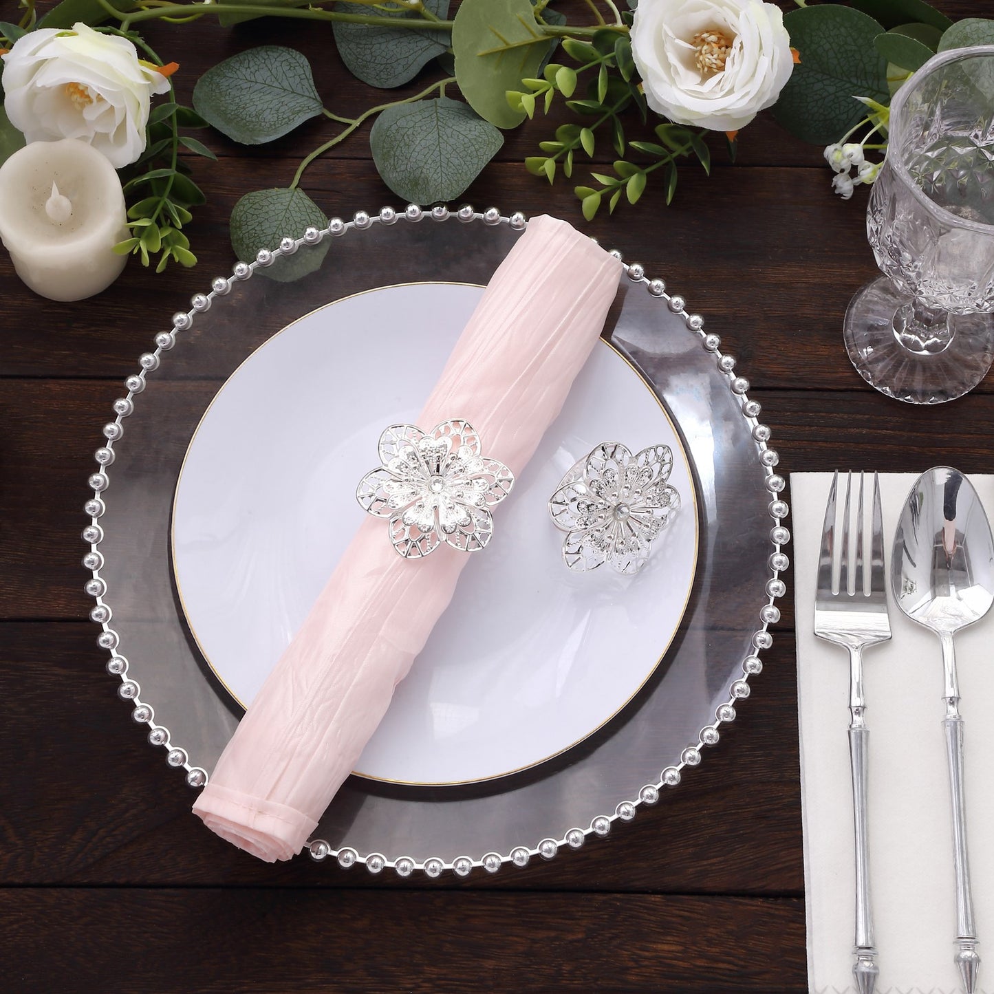 Silver metal hollow sun flower napkin rings on a table setting.