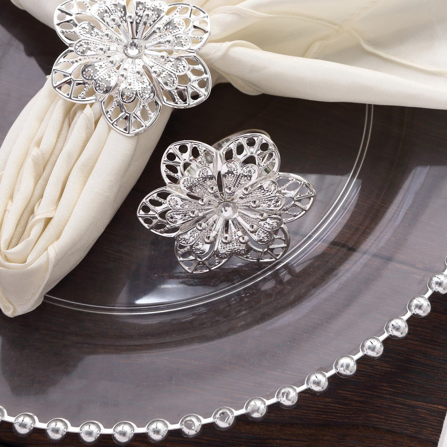 Silver metal hollow sunflower napkin rings on a white napkin.