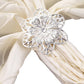 Silver metal hollow sunflower napkin ring on a light fabric napkin. #whtbkgd