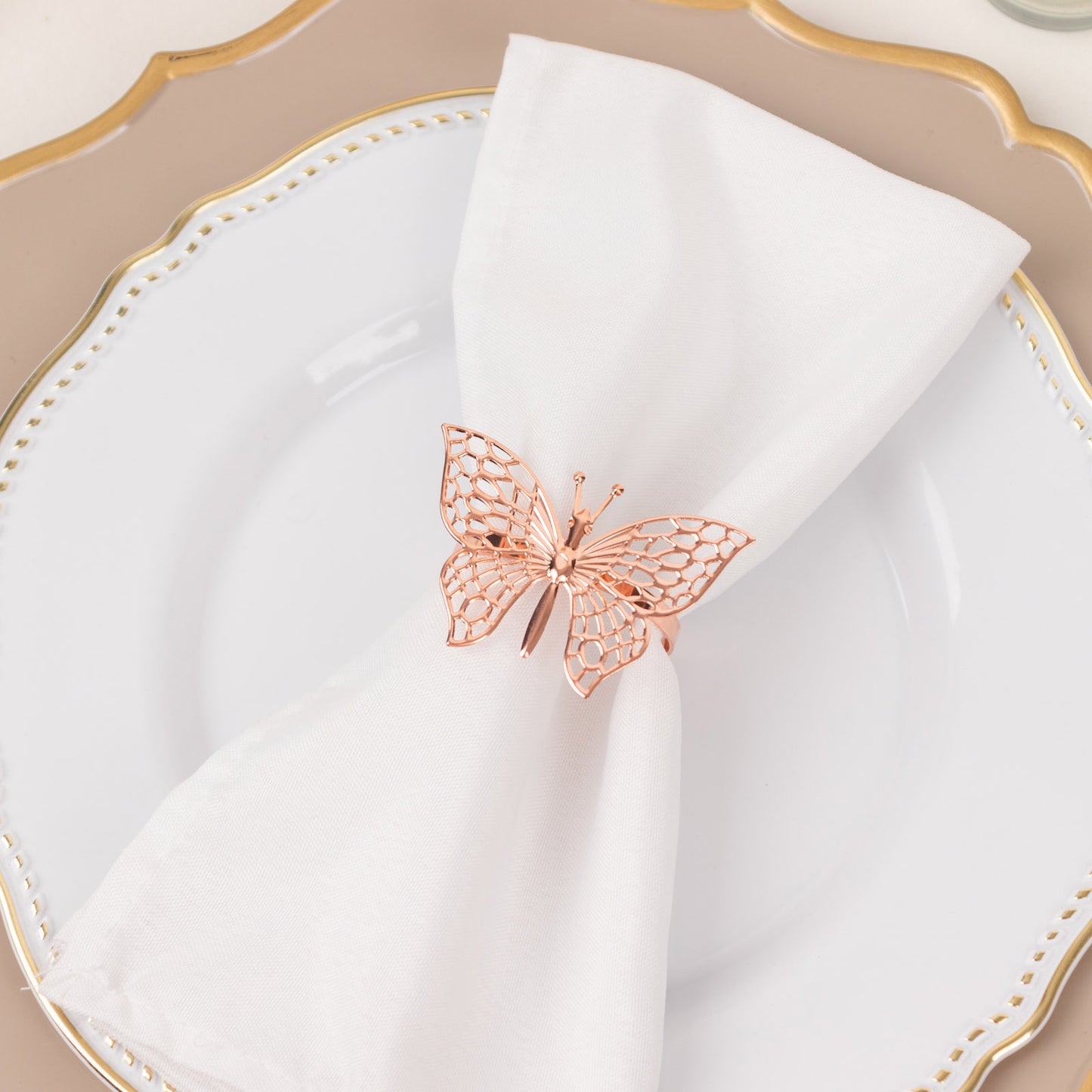 Rose gold butterfly napkin ring on a white napkin.