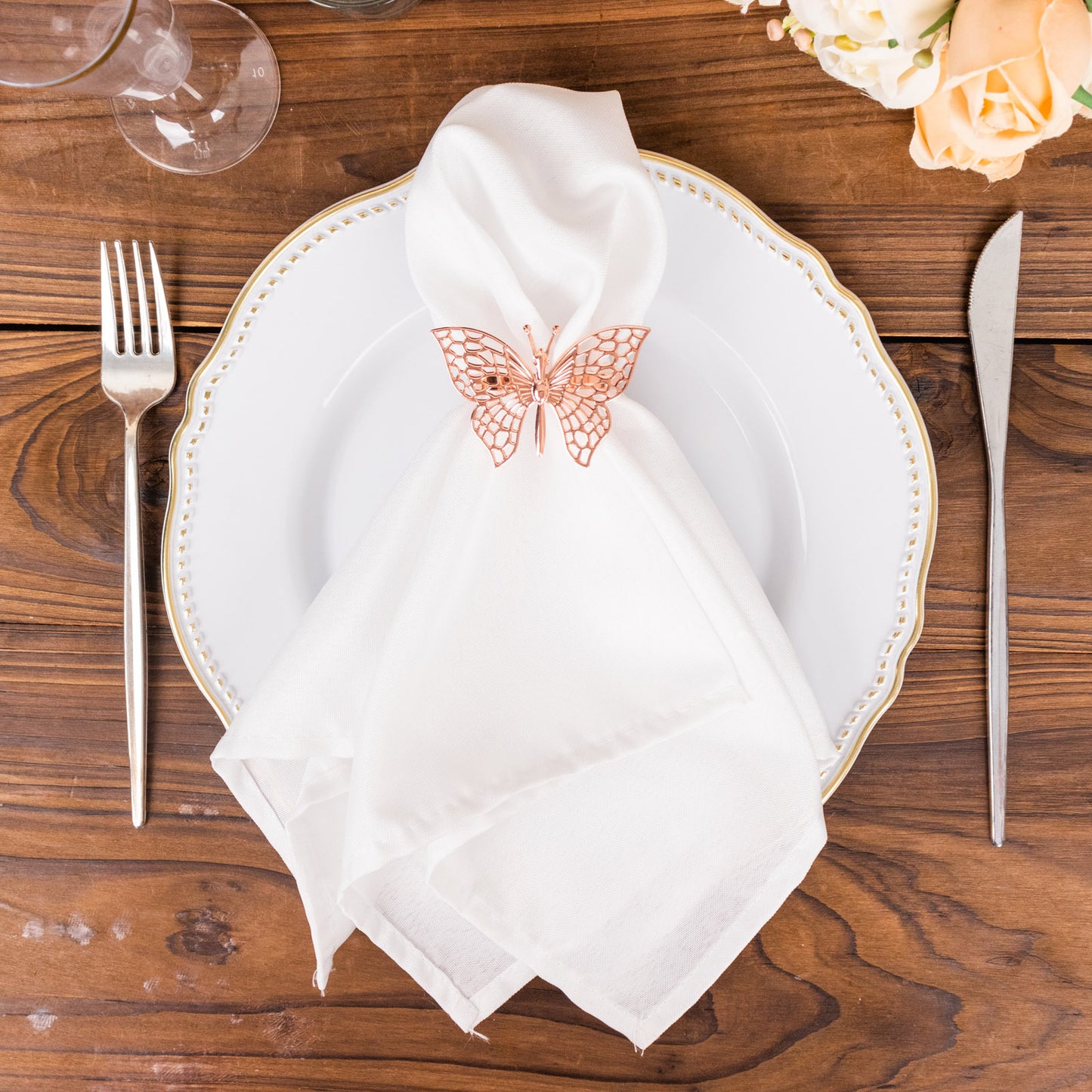 Rose gold butterfly napkin ring on a white napkin and plate.