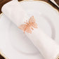 Rose gold butterfly napkin ring on a white cloth napkin.