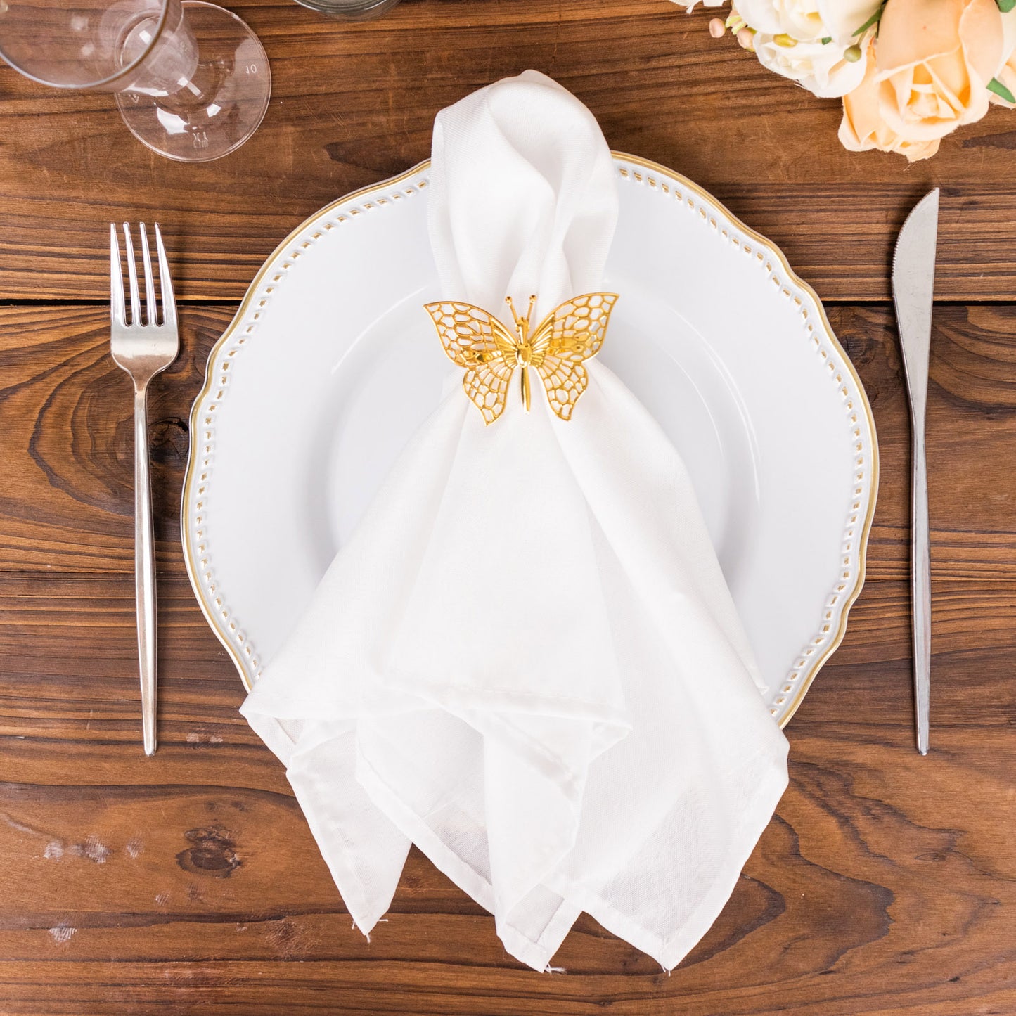 Gold butterfly napkin ring on a white napkin and plate.