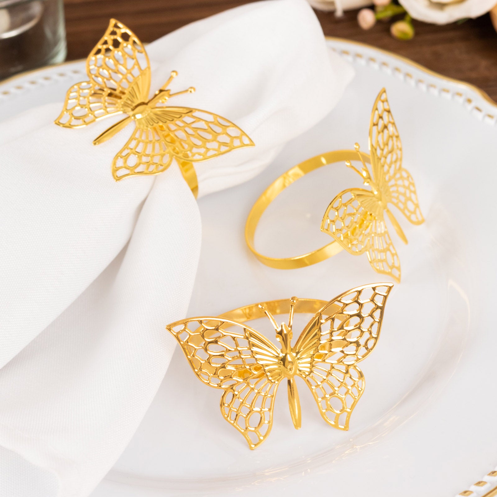 Gold metal butterfly napkin rings on white napkins.