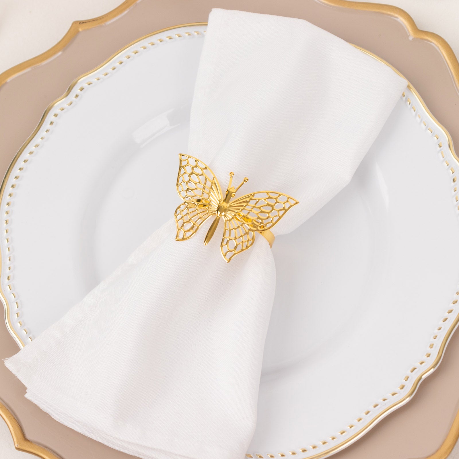 Gold butterfly napkin ring on a white cloth napkin.