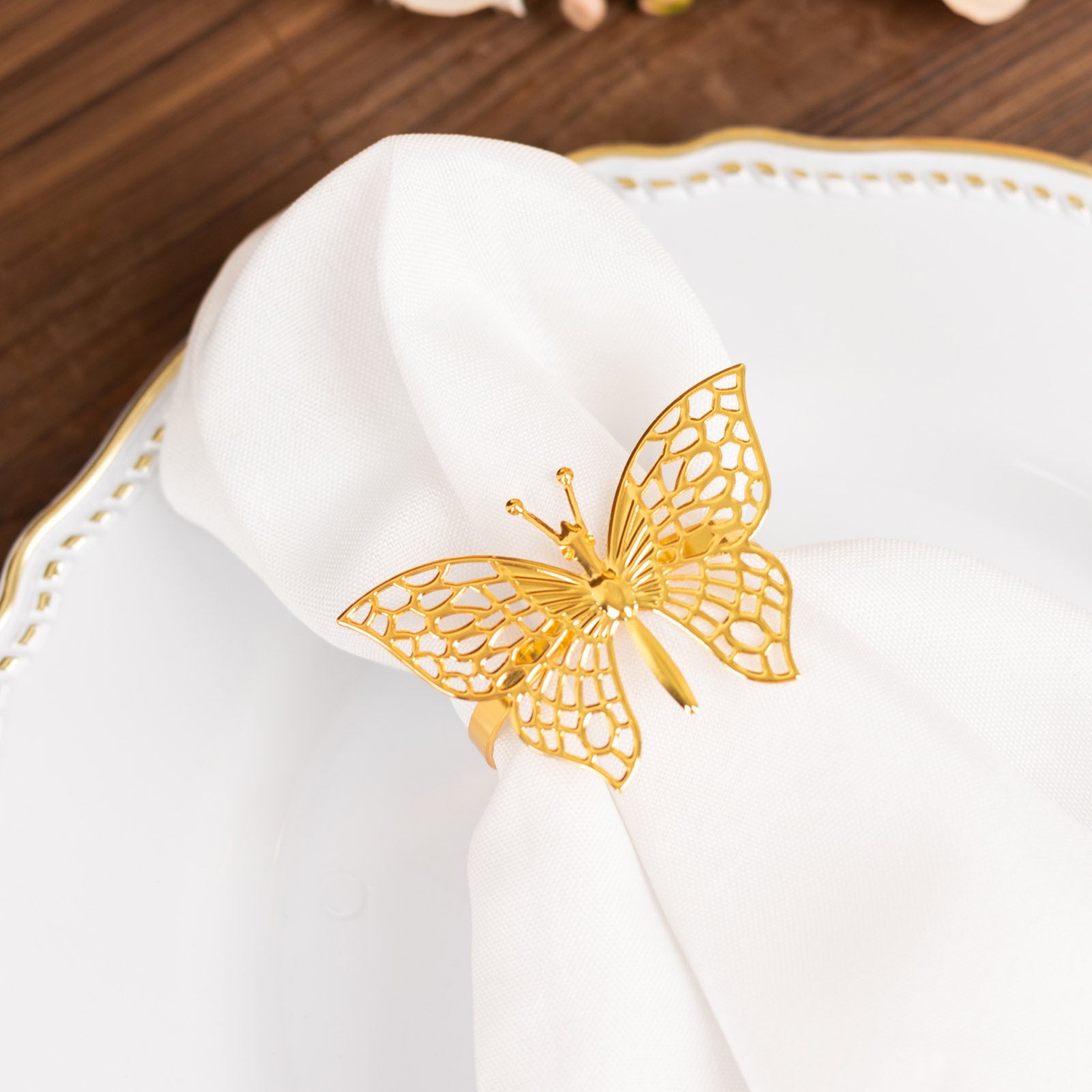Gold butterfly napkin ring on a white cloth napkin.