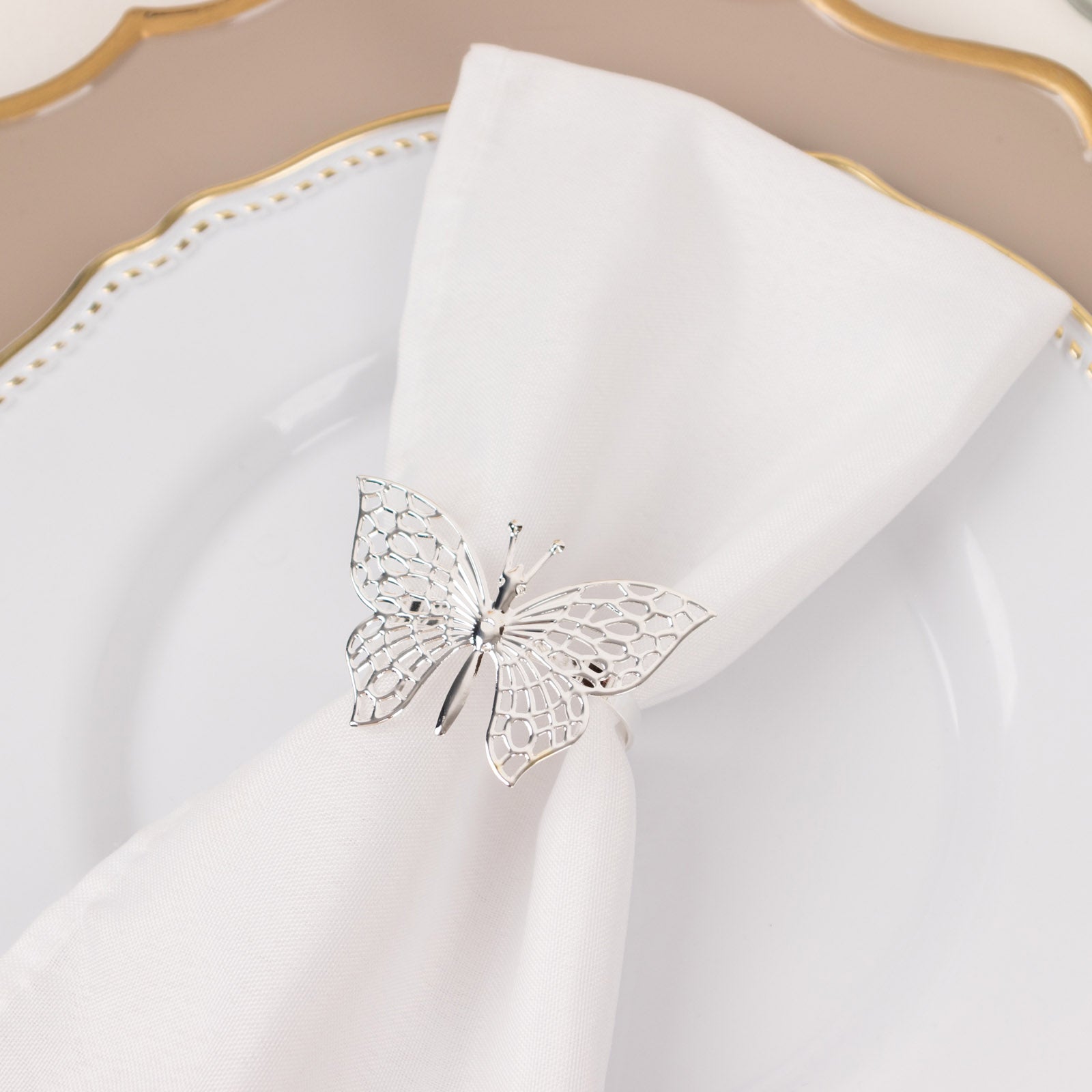Silver butterfly napkin ring on a white cloth napkin.