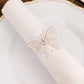 Silver metal butterfly napkin rings on white cloth napkin.